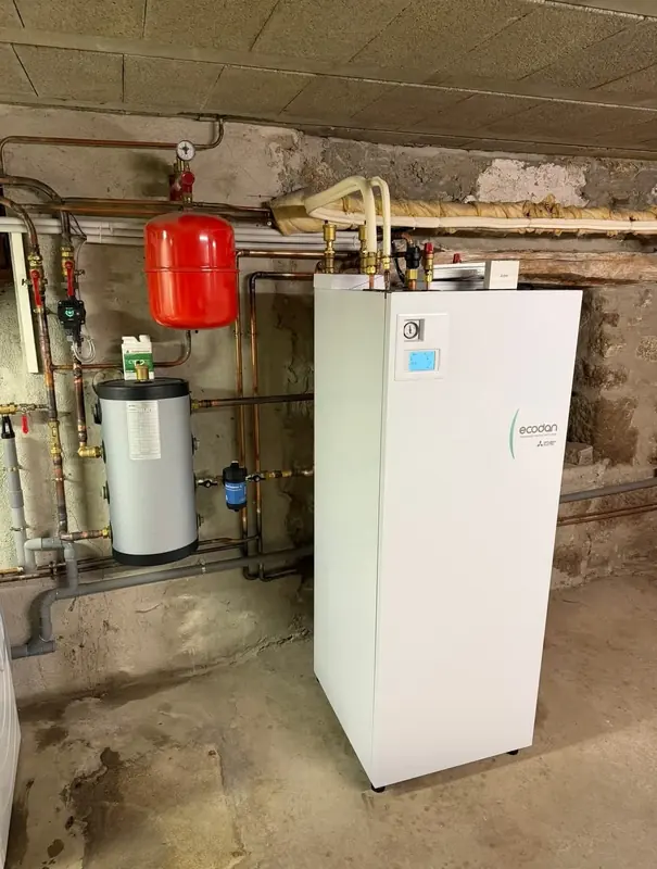 Module hydraulique Mitsubishi Ecodan avec ballon et vase d'expansion rouge dans une cave en pierre